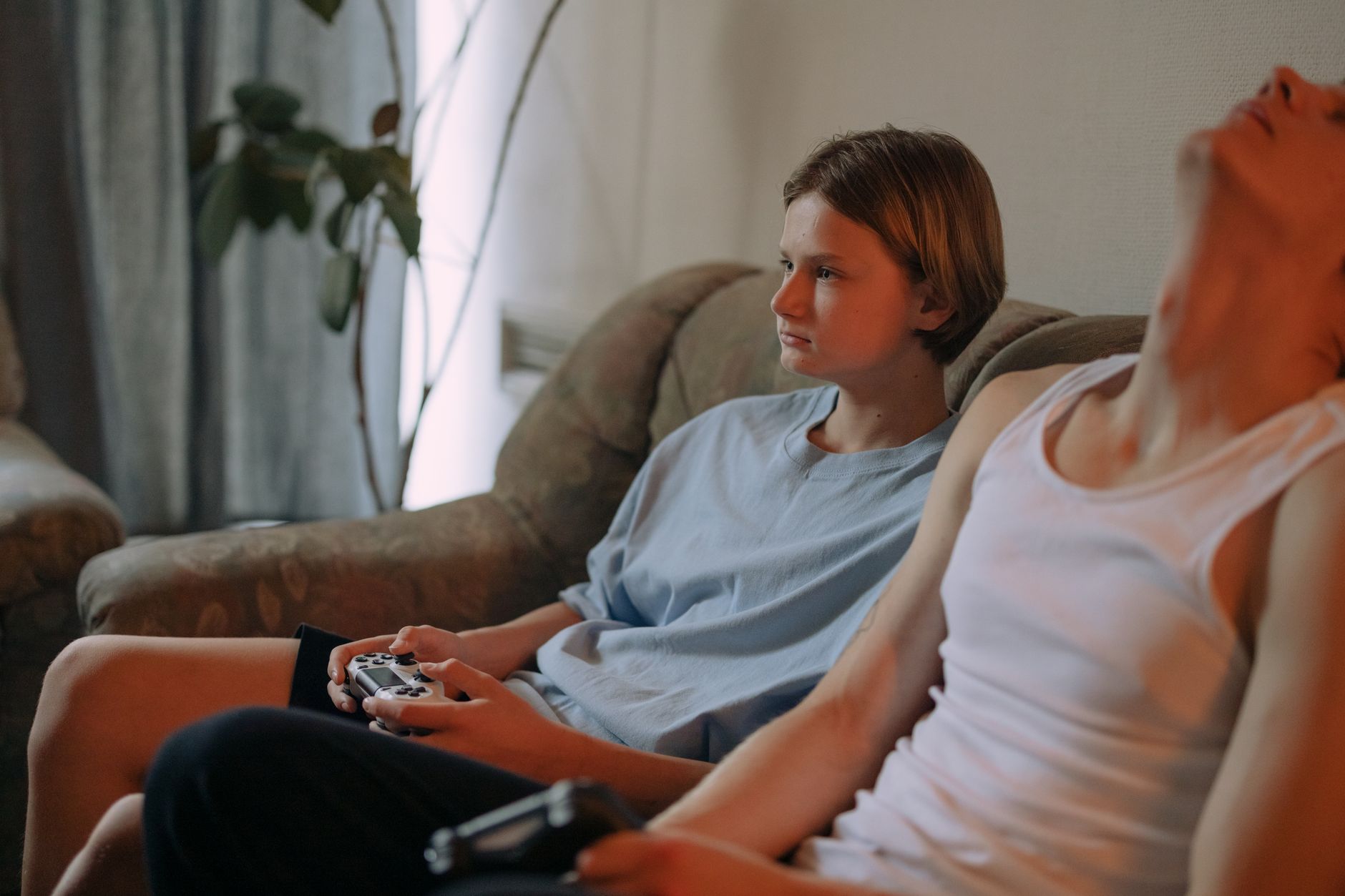 Dwóch nastolatków gra na PS4 w salonie, trzymając pady w dłoniach