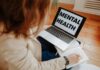 Kobieta na terapii online notuje, obok laptop z napisem Mental Health