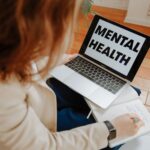 Nowoczesne formy terapii w psychiatrii: od teleporad po terapię wspomaganą aplikacjami Kobieta na terapii online notuje, obok laptop z napisem Mental Health