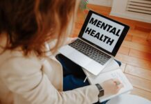 Kobieta na terapii online notuje, obok laptop z napisem Mental Health