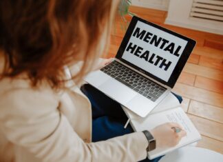 Nowoczesne formy terapii w psychiatrii: od teleporad po terapię wspomaganą aplikacjami Kobieta na terapii online notuje, obok laptop z napisem Mental Health
