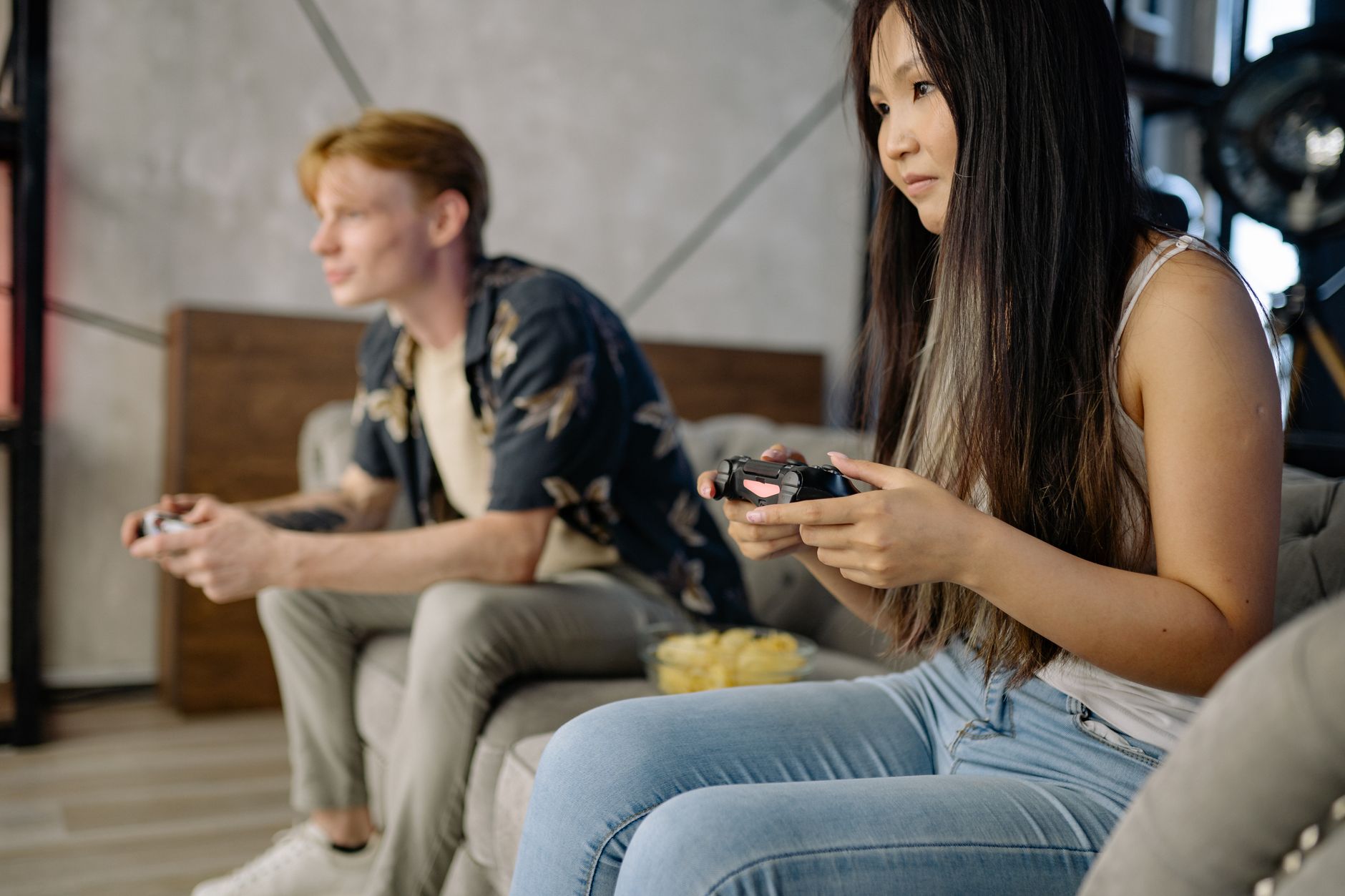 Młodzi dorośli grają razem na PS4 na kanapie w salonie