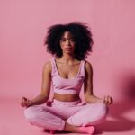Kobieta z afro medytuje w różowym, spokojnym studio